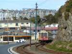 Die Manx Electric Railway erinnert in ihrer Bauform an eine Straßenbahn. Tatsächlich verbindet sie aber einige größere Orte der Isle of Man miteinander und hat dabei eher einen Zug-Charakter: Weit auseinanderliegende Stationen und wenige Fahrten pro Tag. Fahrzeuge und auch Strecken werden im alten Stil gepflegt: Man findet im Fahrgastraum keine Stopp-Knöpfe, Lautsprecher, elektronischen Anzeigen oder andere Neuheiten, die in den letzten Jahrzehnten zum Standard geworden sind; die Schienen sind geschraubt, die Oberleitungen verfügen nicht über Tragseile sondern hängen zwischen den Masten durch. Wären da nicht moderne Straßen und Autos - man könnte sich tatsächlich im Ende des 19. Jahrhunderts wähnen.

Hier hat der Zug gerade Douglas Derby Castle verlassen und arbeitet sich nun den Berg hoch. 23.3.2015