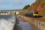 Der Wind am frühen Morgen peitscht hohe Wellen an das Festland: Lokalzug unterwegs vor schöner Kulisse nach Exeter. Dawlish, 18.5.2022