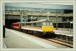 Eine Class 86 noch in BR Intercity-Lackierung wartet mit einem  Virgin -Schnellzug auf die Abfahrt in Euston.