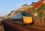 Triebzug der GWR vor einem schönen Hintergrund mit einem typisch englischen Steinhaus und roten Felsen. Dawlish, 18.5.2022