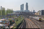 Ein Triebzug der Class 378 der London Overground hat am 22. April 2019 gerade die Station Shoreditch High Street verlassen, während der Greater Anglia 317 653 auf der Great Eastern Railway Richtung Liverpool Street Station fährt.