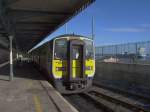 Diesel-Triebzug 2602 am 15.02.2005 in der Endhaltestelle auf der Insel Corbh, sie liegt in der Mndung des Flusses Lee vor der Stadt Cork, das Containerschiff kommt von Cork und fhrt in Richtung Atlantik. Die Bahn fhrt ber Brcken und Dmme vom Festland zur Insel.
