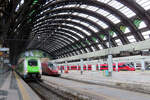 Farbige Züge im Bahnhof Milano Centrale: ein grün-weisser Regionalzug und zwei Hochgeschwindigkeitszüge warten auf die Abfahrt.