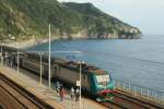 E 464 300 steht mit der Kulisse der Riviera di Levante im Bahnhof von Corniglia; 25.04.2009