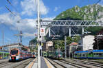 Farbenpr�chtige Rush-Hour in eindr�cklicher Landschaft in Lecco: Links der Regio von Milano nach Tirano, in der Mitte warten zwei Z�ge auf die Abfahrt in Richtung S�den, rechts am Bahnsteig der Regio