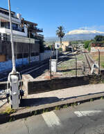 Der letzte Schnappschuss unserer Fahrt mit der Circumetnea FCE aus dem Busfenster: Bei der Fahrt von S.M. Licodia Sud nach Nesima (Catania) befuhren wir einen Bahn�bergang beim Bahnhof Paterno mit dem rauchenden �tna im Hintergrund. Die Gleise sind also im April 2026 im Bahnhof noch vorhanden. Ich bin gespannt, bis wohin die Z�ge Richtung Catania in Zukunft fahren werden. Paterno, 28.4.2026