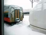 Serie 751: Von den heute ausgegliederten 2 Wagen pro Zug ist es praktisch unmöglich, eine Aufnahme zu machen. Ein kurzer Blick aus einem vorbeifahrenden Zug zeigt die sonst nie zu sehende Stirnwand eines Motorwagens MOHA 751. Gut zu erkennen ist, welch harten Witterungsbedingungen diese abgestellten Wagen heute ausgesetzt sind. Bei Aomori, 12.Februar 2013. 