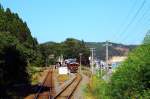 Die Sanriku-Bahn: Einfahrt in die Station Tarô, wo kurz nach dem Tsunami im Rahmen erster zaghafter Wiederbelebungsversuche der Bahn das ganze Ausmass der Tragödie zu sehen war. Im Hintergrund sind die riesigen Bauarbeiten zum Wiederaufbau und besseren Schutz des Gebiets zu sehen. In der Station wartet ein Dreiwagenzug mit dem neuen Salonwagen Z1 (Baujahr 2014) mit japanischer Inneneinrichtung (man sitzt wie in einem japanischen Zimmer auf weichen Riedgrasmatten am Boden). 27.September 2014.  