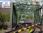 Fremde Züge auf der Keikyû-Linie: Die Chiba New Town –Bahn. Zug 9011 auf der Brücke über die JR-Geleise in Tokyo-Shinagawa. 28.Oktober 2011. Der Text am Schild an der Schranke übersetzt sich sinngemäss als  Bitte haben Sie etwas Geduld . 