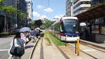 Kumamoto City Tram Typ 0800 Wagen 0802 der Linie B an der Haltestelle Torichosuji, 24.08.2016     Im Hintergrund die Burg Kumamoto.