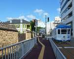 Die Strassenbahn von Nagasaki: Wagen 372 (Serie 371-377) fährt an der Nachbildung der einstigen holländischen Niederlassung (bis 1859 der einzige Ort, Europa und dem Westen zu begegnen) auf der Insel Dejima vorbei; das überbaute Dejima-Gebiet ist heute kaum mehr als Insel zu erkennen. 8.August 2013. 