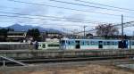 Serie 115 des zentraljapanischen Hochlands: Der Endwagen eines 6-Wagenzugs KUHA 115-1224 in Kobuchizawa; im Hintergrund ein Dieseltriebwagen der Koumi-Linie, Japans höchstgelegener Bahnlinie.