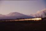 Serie 169: Bei Sonnenuntergang ein Zug vor dem Asama-Vulkan. Von rechts das Motorwagenpaar (Endwagen KUMOHA 169-3 und MOHA 168-3), dann die 2 Luxuswagen und der Speisewagen. Bei Naka Karuizawa, 13.Februar 1973. 