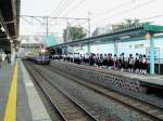 Serie 701 des Bezirks Morioka: Misawa, Hunderte von Schüler warten auf den Zug, die Jungen und die Mädchen in Gruppen getrennt. Einfahrt von Zug 701-1005. 8.Juli 2010.  