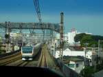 Serie 233: Ein Zug der Chûô-Linie (die Tokyo mit den westlichen Vororten verbindet; die Züge sind mit orangem Streifen gekennzeichnet) braust über die Dächer von Tokyo hinweg;