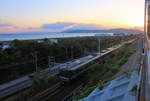 Blick von der S-Bahnlinie durchs Kansai Gebiet auf die Grosse Brücke über die Akashi-Meeresenge. Im letzten Abendlicht fährt ein Eilzug (Triebwagenzug Serie 223) in Richtung  Grosse Akashi-Brücke, die sich um diese Uhrzeit in Dunst hüllt. Der Zug fährt hier auf der mittleren der drei Doppelspurebenen (für die schnellen JR-Züge), darunter ist die Doppelspur für JR-Züge mit Halt an allen Stationen zu sehen, und die Aufnahme selbst stammt von der obersten Doppelspurebene, auf der hier die privaten Züge des Sanyô-Konzerns durchfahren. 6.November 2018   SANYÔ HAUPTLINIE 
