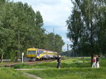 Wilder Bahnübergang in Lettland: Trotz der Kurven und relativ hohen Geschwindigkeiten sind hier Betonplatten im Gleisbereich verlegt, Warnschilder rufen zum Beachten der Züge auf.