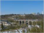 . Pfaffentaler Viadukt – Auch in der Stadt Luxemburg waren am 15.03.2013 noch Schneereste zu sehen, als eine Doppeleinheit Z 2200 das Pfaffentaler Viadukt in Richtung Norden gefuhr. Von den vier Eisenbahnbrcken in der Stadt Luxemburg, ist der Pfaffentaler Viadukt der zweitgrte, er hat eine Lnge von 257 Meter und besitzt 12 Bgen.

Im Hintergrund sieht man einerseits noch berreste der Festung Luxemburg (das Fort Thngen), andererseits das moderne Centre Europen auf dem Kirchberg.
(Jeanny)
