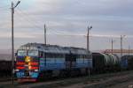 2TE116CHM013 wartet mit einem Güterzug auf einem kleinen Bahnhof auf der Transmongolischen Eisenbahn.