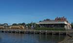 NL/ Bf. Enkhuizen, 9.8.2015. Auch dieser Bahnhof liegt direkt am Hafen. Blick von den Kaianalgen zum Empfangsgebäude. Am Bahnsteig ein VIRM.