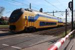 Zwei VIRM Doppelstockeinheiten fahren am 14.04.2015 mit dem IC 856 (Maastrich - Schagen) aus dem Bahnhof Roermond am Bahnübergang vorbei.