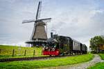 Lok 26 der ehemaligen Limburgsche Tramweg-Maatschappij passiert mit einem Lokalbahnzug die Mühle  De Herder  in Medemblik, Noord-Holland (22.10.2021)