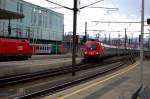 Kurz vor einem heftigen Regenschauer bringt 1016 032-3 einen Eurocity unter das rettende Bahnsteigdach. Bedrohlich das Licht aber treffend fr die Farben. Links ein noch auf Fahrgste wartender  City-Shuttle  mit dem  Portugal-Stier .