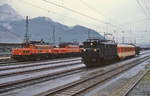 An einem regnerischen Augusttag 1982 stehen eine 1670 mit einem kurzen Personenzug und ein 1020-Doppel mit einem Güterzug im Bahnhof Bludenz abfahrbereit in Richtung Arlberg