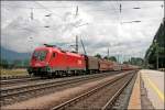 Die Sonne kommt etwas heraus als 1116 035 mit einem langen Gterzug durch den Bahnhof Brixlegg in Richtung Hall i.Tirol fhrt.