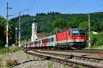 Das Motiv einmal aus der  Froschperspektive : Die gut gepflegte 1144.223 läuft mit ihrem REX 1785 nach Linz HBF in den Bahnhof Wernstein ein. Im Hintergrund die Pfarrkirche zum hl. Georg (12. Juni 2015).