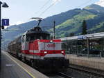 1163 010 Berta mit vier Güterwagen bei Durchfahrt durch Brixen im Thale in Richtung Kitzbühel, im Hintergrund die Hohe Salve (1828 m); 30.08.2019
