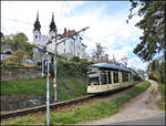 ET 504 hat hier am 22.04.2026 um 15.34 Uhr gerade den Bergbahnhof auf dem Pöstlingberg verlassen und passiert bei der Talfahrt die im Hintergrund aufragende Wallfahrtsbasilika der sieben