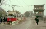 Wien Wiener Verkehrsbetriebe Allerheiligenverkehr 1975: An der Haltestelle am 2. Tor des Zentralfriedhofs sieht man zwei Zugabfertiger mit ihren Signalflagggen. Rechts im Bild sieht man den Überwachungsturm. Auf dem Gleis, das Richtung Innere Stadt führt, hält ein Zug der SL 22 (E1 4493 + c2/c3) - der Zug hat Reichsbrücke als Ziel. - Scan von einem Farbnegativ. Film: Kodacolor II. Kamera: Kodak Retina Automatic II.