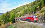 Im warmen Spätnachmittagslicht des 26.10.2026 war 1216 020 mit dem RJ 87 nach Bologna Centrale in den herbstlichen Wäldern bei Gries am Brenner unterwegs.