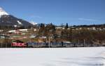 V 100 der Salzburger Lokalbahn SLB V 87 mit Ganzzug Container Kaindl Richtung Salzburg, Salzburg-Tiroler-Bahn KBS 200 Freilassing - Salzburg - Saalfelden, fotografiert am 07.03.2012 vor den  Sieben Mhlen  bei Pfarrwerfen --> Dies sind die 7 kleinen Holzhuschen oberhalb des 2. Wagens, von denen eine Sage erzhlt, dass der Herrgott als Wanderer hier persnlich gerastet und die Mllerin fr ihre Hilfsbereitschaft belohnt hat.  