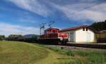 Der SLB Oldtimer E 62 (Baujahr 1952) durchfährt -mit einem für Lokalbahnverhältnisse recht stattlichem Güterzug- die Haltestelle Muntigl Richtung Salzburg Itzling. Aufgenommen am 27.08.2015.