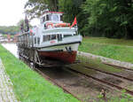 Dieses Schiff hat die Abgangssstation Przystan soeben verlassen und wird auf den ersten Rollberg gezogen. Der Oberländische Kanal bzw Oberlandkanal verbindet mehrere grössere und kleinere Seen sowie mehrere Städte und Dörfer. Um die Höhenunterschiede zwischen den einzelnen Gewässern zu meistern (total 99 Höhenmeter), wurden Mitte des 19. Jahrhunderts fünf so genannte Rollberge gebaut. Auf diesen 'geneigten Ebenen' wird das Schiff in speziellen Schienenwagen mittels Standseilbahnen transportiert, angetrieben von Wasserrädern. Die Spurbreite ist, je nach Quelle, 3.14m oder 3.27m. Teilweise führt ein Wanderweg direkt neben dem Trassee vorbei, dies wird beim Fotografieren sehr geschätzt. Ein sehr spezielles und höchst interessantes Transportmittel! Przystan (Pristanien), 22.9.2021