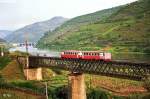 Triebzug 9718/9717 auf der Brcke ber den Rio Corgo nahe Rgua (10. Mai 1988). Die Brcke wird von der breitspurigen Dourotal-Linie und der schmalspurigen  Linha do Corgo  gemeinsam benutzt. Dazu gibt es weiter unten noch ein Foto von Gnther Glauz.