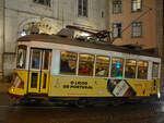 Dieser historische Straßenbahnwagen ist hier im Jahr 2016 an einem nassen Dezemberabend in Lissabon unterwegs.