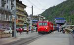 Am trüben Morgen des 06.05.2024 fährt HGe 4/4 II 109 mit dem Panorama-Express nach St. Moritz vom Bahnhofsvorplatz in Brig ab