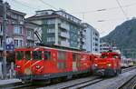 Zwei Fahrzeuggenerationen der Matterhorn-Gotthard-Bahn mit unterschiedlichen Energieversorgungskonzepten treffen sich am 09.05.2024 in Brig: Links der 1984 beschaffte elektrische Gepäcktriebwagen Deh 4/4 II 95, daneben die Elektro-Akkulok Tea 2/2 801, die 2020 in Dienst gestellt wurde