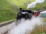 Viel Dampf in der Station Furka (2160müM): Der Dampfzug von Oberwald nach Realp mit der Lok FO 4 (ex Furka-Oberalp-Bahn) und den roten Wagen fährt ab. Furka, 28.7.2022