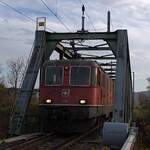 Schweizer Zucker AG, Zuckerfabrik Aarberg, Kampagne 2025: Re 4/4 II 11304 + Re 4/4 II 11300, Zug 38042 Aarberg-Dietikon (via Kerzers-Burgdorf), Lokzug zum Abholen eines Rübenzuges, Hagneck-Kanal-Brücke, Aarberg, 15. November 2025. Vertragspartnerin für die Bahnlogistik der Schweizer Zucker AG ist die TR Transrail AG, Frauenfeld. Diese arbeitet mit Mietloks: Die Basis im Verkehr ab und nach Aarberg bildeten die meiste Zeit zwei Re 420 von SBB Personenverkehr, zwei Re 465 der BLS und zwei Akiem-189er (fall- und zeitweise weitere Loks).