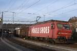 Schweizer Zucker AG, Zuckerfabrik Aarberg, Kampagne 2025: Re 456 094-2 (Mietlok, DSF Verein Depot Schienenfahrzeuge Koblenz, ex SOB) + 9 Eaos/Eas, Zug 69465 Alle Cargo-Porrentruy-Delémont, Porrentruy, 12. November 2025. Die Ladestelle Alle Cargo bedienen im Rübenverkehr jeweilen die CJ, Chemins de fer du Jura, mit zwei Zugpaaren je Tag Delémont-Alle Cargo-Delémont, währenddem TR Transrail AG, Frauenfeld, die Wagen mit einem Zugpaar Aarberg-Delémont-Aarberg anliefert und abholt. Beide Unternehmen arbeiten mit Mietloks. Das Äussere der Re 456 094-2 wirkt inzwischen vernachlässigt: Die Farbe ist verblasst, das beworbene Schuhhaus existiert nicht mehr. Dazu passend und gewohnheitsmässig hat der an diesem Tag diensthabende und auf der Lok mitfahrende Rangierer  seine  Hälfte der Frontscheibe  apart  dekoriert. Autofahrern sei von einer Nachahmung abgeraten. Zuvor hatte der Lokführer während der Wartezeit am Bahnsteig die Frontscheibe aussen und innen sorgfältig gereinigt.