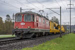 Re 4/4 II 11141 des DSF ist mit einem Kran am Haken unterwegs von Luzern nach Koblenz, aufgenommen am 30.03.2023 bei Birr AG.
