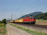 Die Re 4/4 11272 am 28.06.2011 mit einem Postzug unterwegs bei  Oensingen. 