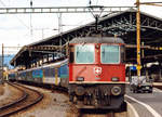 SBB: Ein langer und bunt zusammengewürfelter Reisezug der speziellen Art mit einer erkennbaren grünen Re 4/4 II als Zwischenlok im Bahnhof Lausanne am 1.