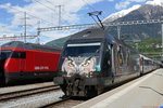 Die wartende Re 460 105 mit VSLF Werbung am IR nach Genf, im Hintergrund die Ausfahrende Re 460 111 mit dem IC nach Romanshorn, am 15.5.2016 in Brig.