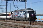 Re 460 028-4, mit einer SBB Personalwerbung, durchfährt den Bahnhof Muttenz. Die Aufnahme stammt vom 10.03.2017.