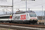 Re 460 075-5, mit der Léman 2030 Werbung, durchfährt den Bahnhof Muttenz.